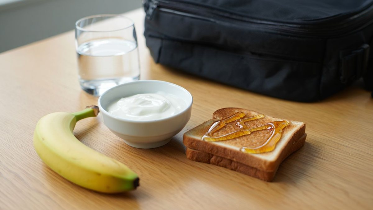 Collation sportive simple avec banane bol de yaourt et verre d’eau sur table lumineuse sans texte ni marque