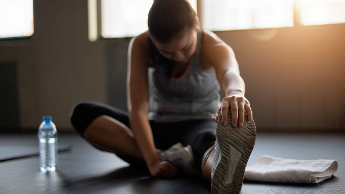 Sportif en récupération après l’entraînement avec étirements doux et bouteille d’eau