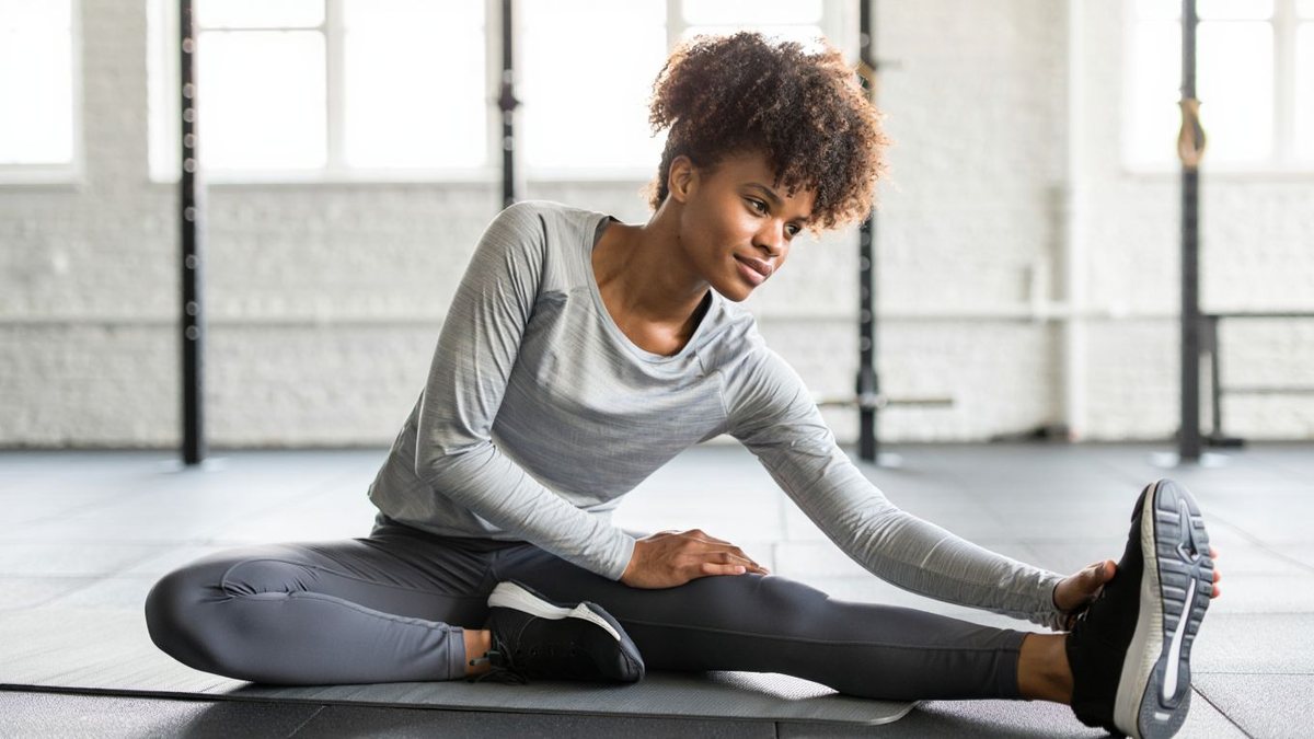 Sportive réalisant une mobilité douce sur tapis dans une salle lumineuse
