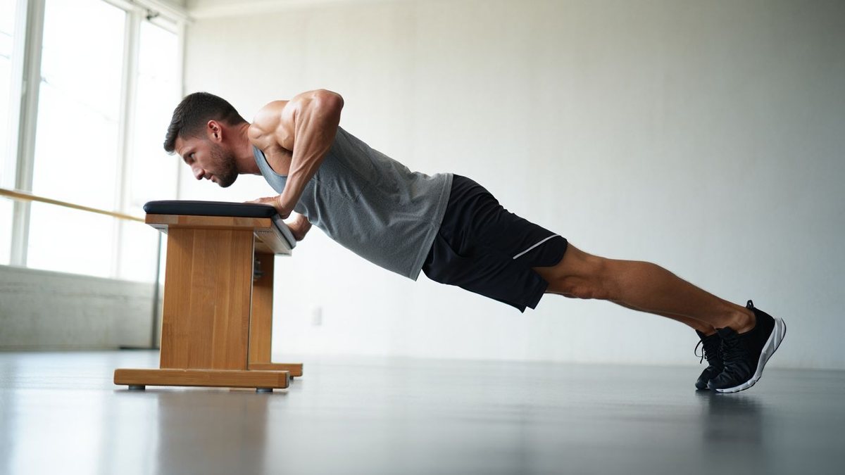 Sportif amateur réalisant des pompes inclinées dans une salle lumineuse sans texte ni marque visible