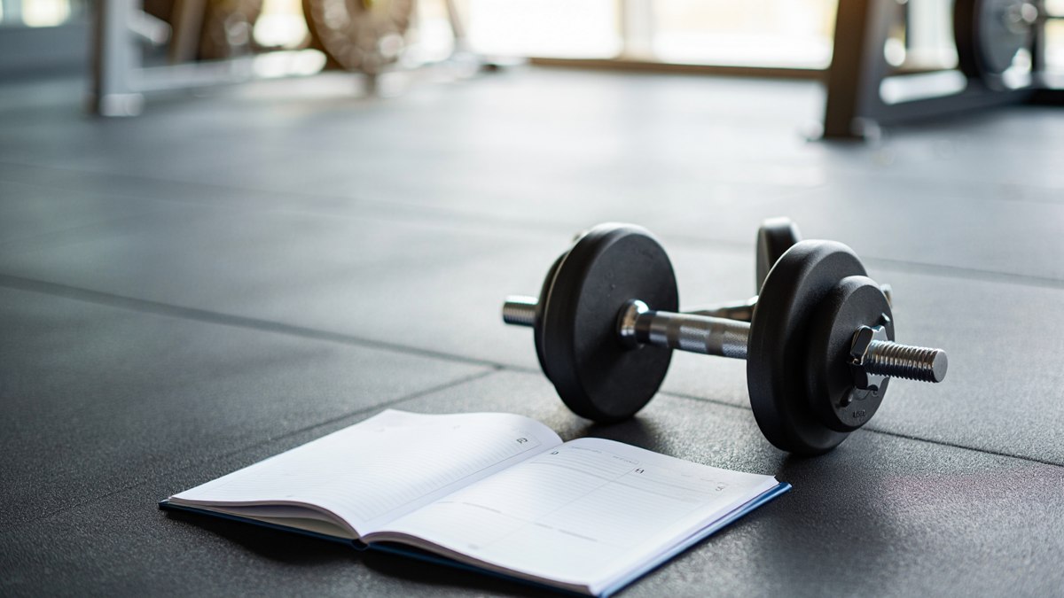 Haltères et carnet d’entraînement pour organiser ses séances de musculation