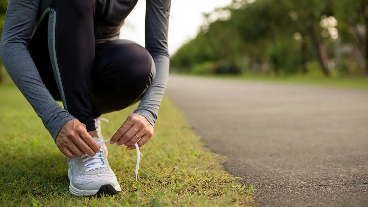 Coureur qui lace des chaussures de running sur un chemin