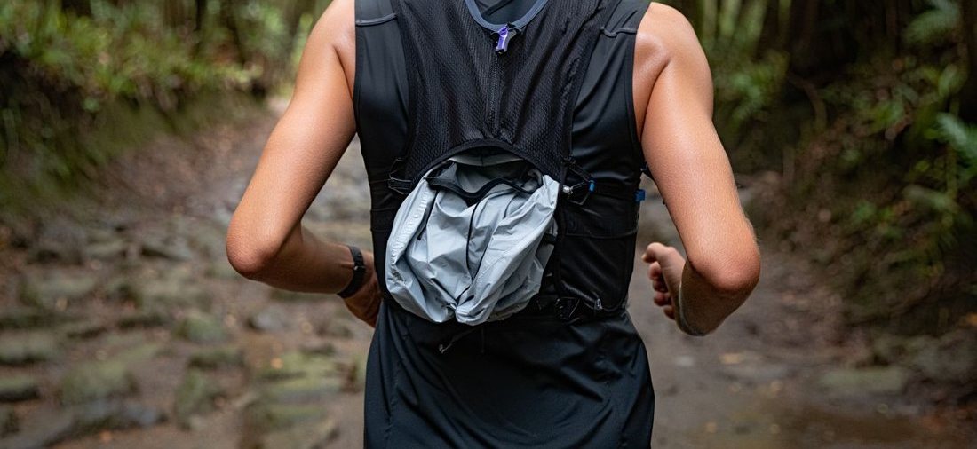 Traileur de dos avec sac d’hydratation et veste sur sentier forestier