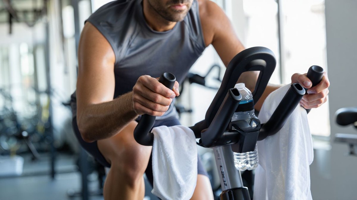 Sportive amateur pédalant doucement sur vélo d appartement après une séance jambes dans une salle lumineuse sans marque visible