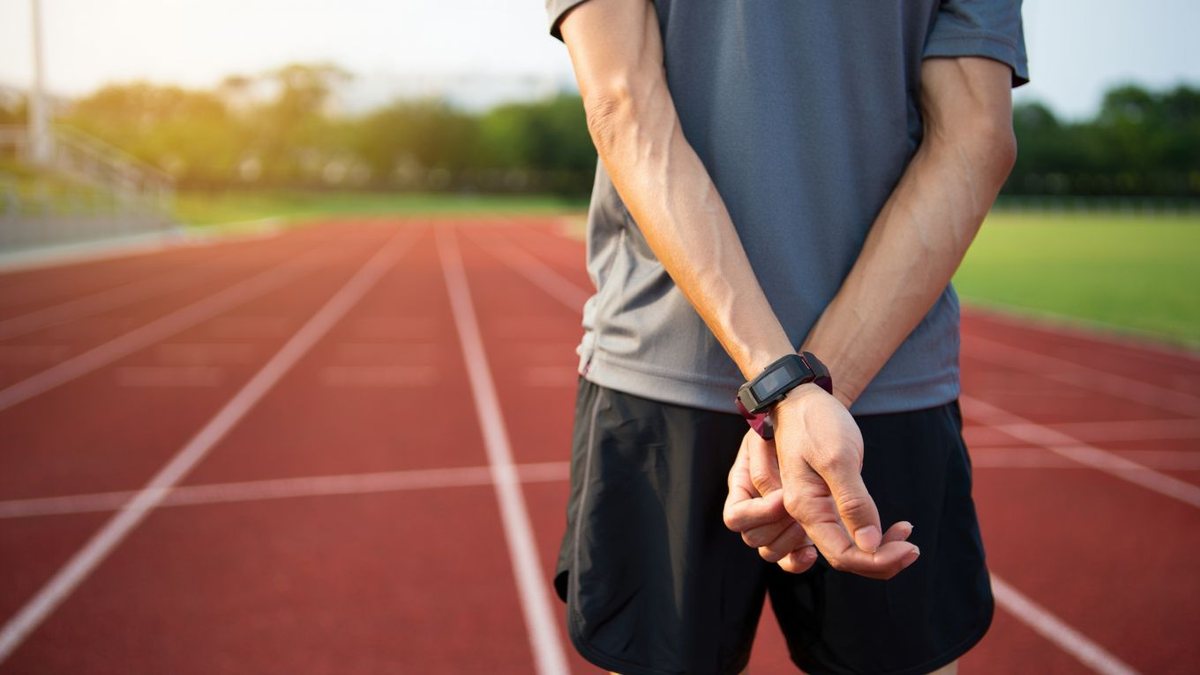Coureuse amateur terminant un footing sur piste extérieure avec montre discrète sans texte ni marque visible