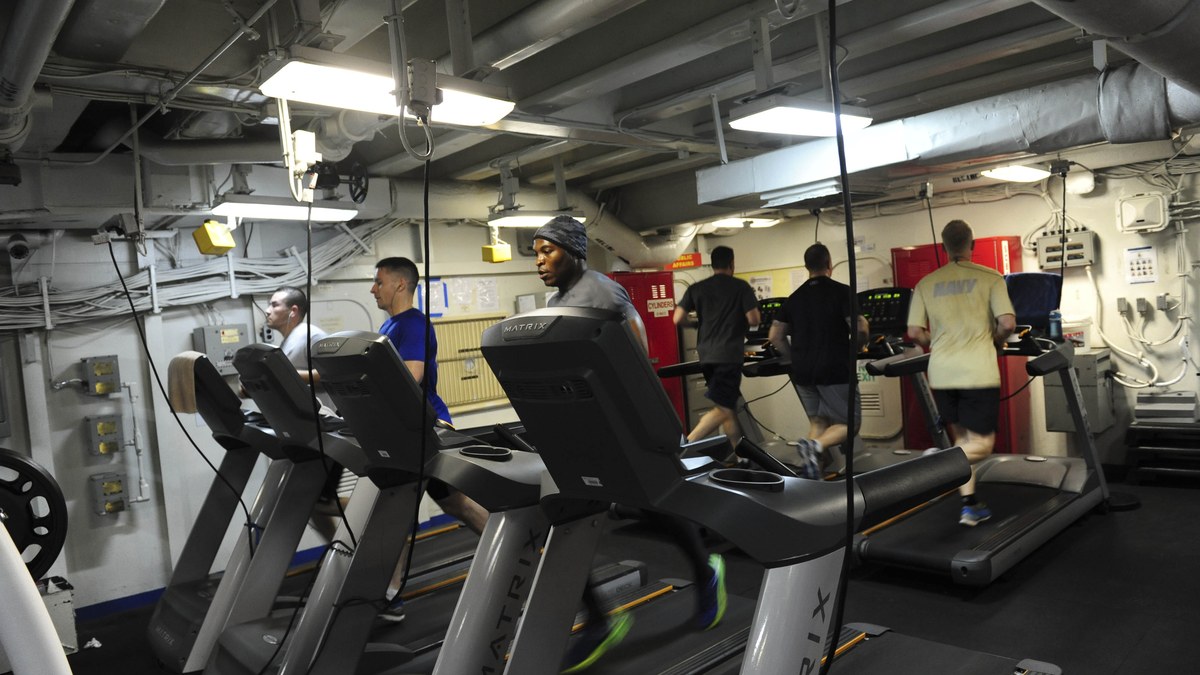 Sportif adulte sur tapis de course au lever du jour dans une salle claire sans texte ni logo
