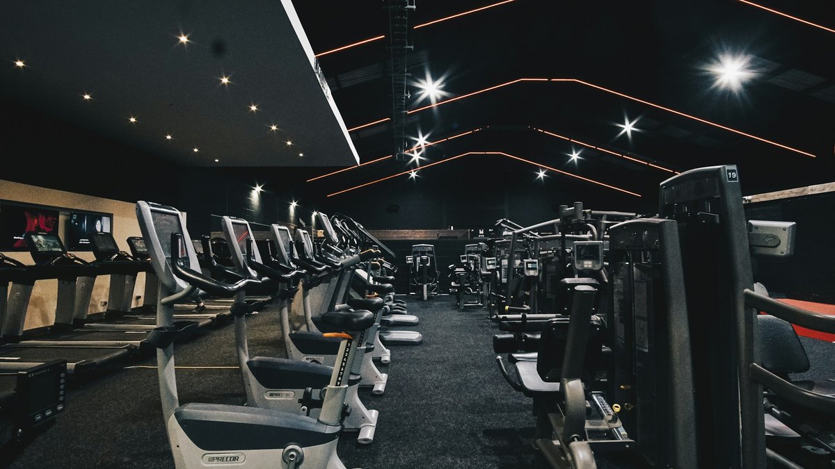Sportif amateur sur vélo d’appartement après une séance de musculation dans une salle lumineuse sans marque visible