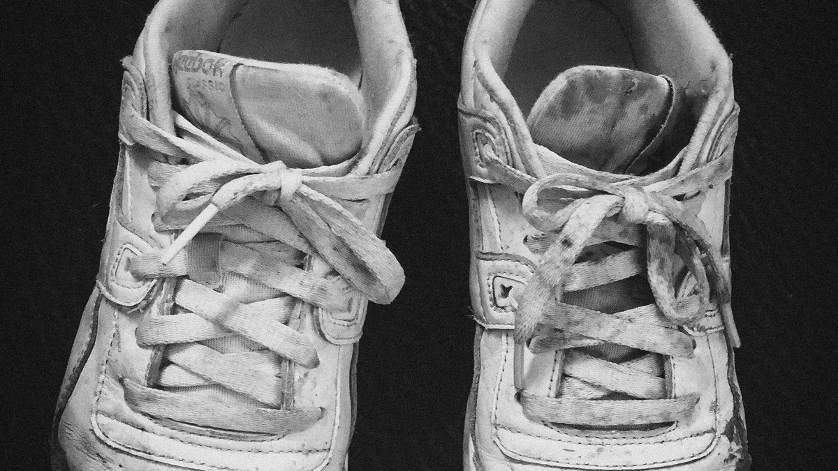 Chaussure de running usée tenue par un coureur après une sortie, semelle visible sans marque ni texte