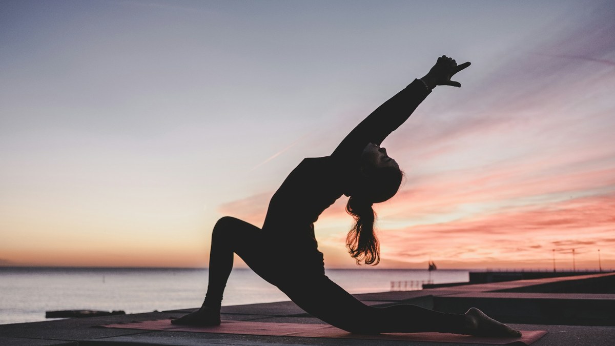 Sportive réalisant une routine de mobilité des hanches sur tapis avant une séance jambes
