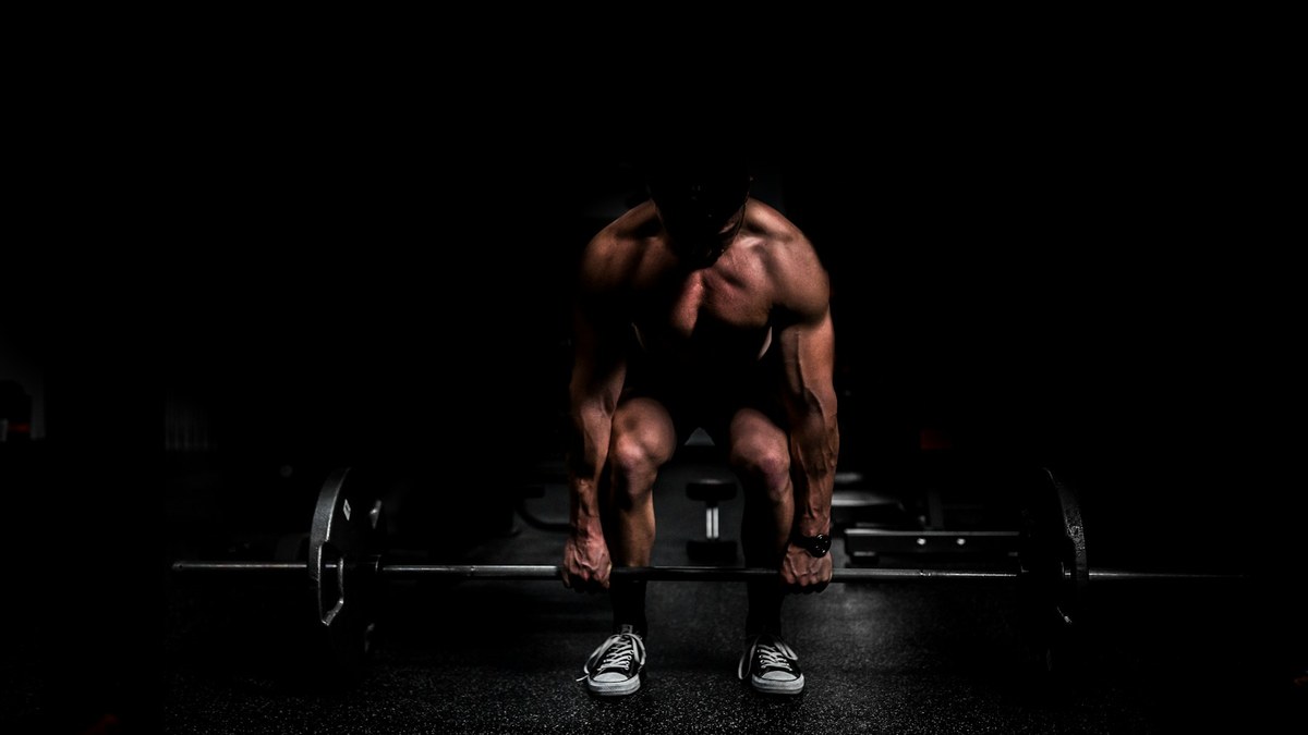 Sportive réalisant des montées sur pointes contrôlées avec haltères dans une salle lumineuse