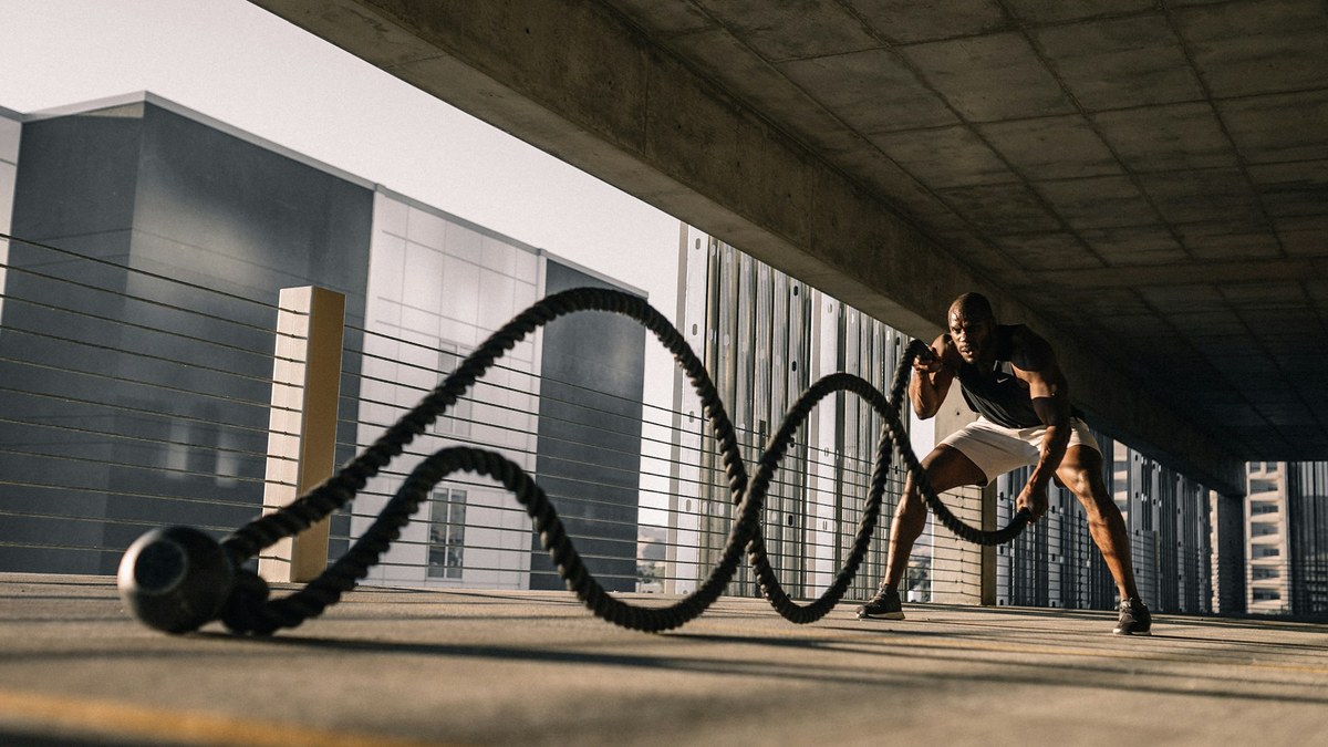 Athlète utilisant un rameur indoor après une séance de musculation dans une salle lumineuse
