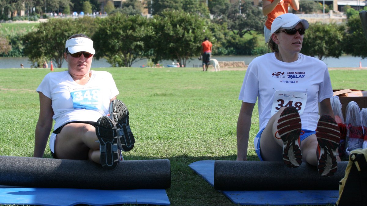 Sportive utilisant un rouleau de massage pour récupérer les jambes