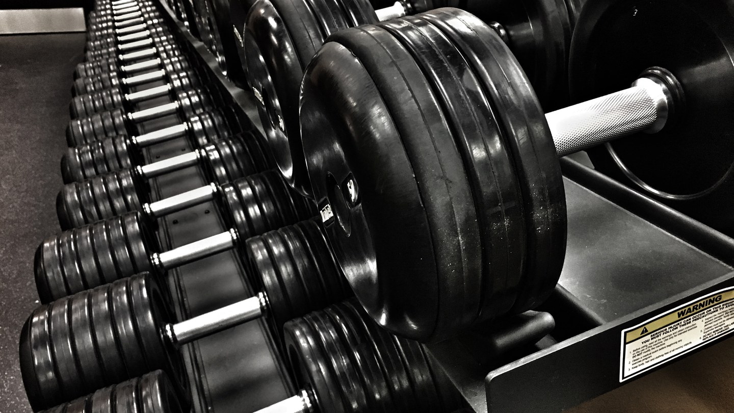 Débutante consultant son programme de musculation hebdomadaire dans une salle de sport