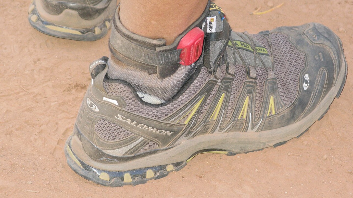 Paire de chaussures de running usées vue de dessous sur fond sportif sobre